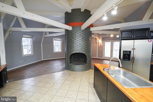 kitchen with sink, light tile patterned floors, butcher block countertops, stainless steel fridge, and rail lighting