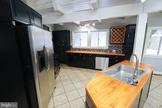 kitchen with backsplash, appliances with stainless steel finishes, beam ceiling, sink, and light tile patterned flooring