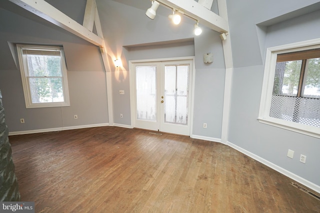 interior space with a healthy amount of sunlight, french doors, vaulted ceiling, and wood-type flooring