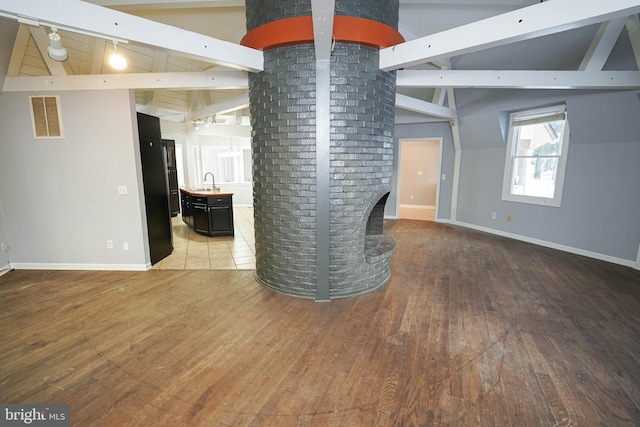 interior space with sink, wood-type flooring, and lofted ceiling with beams