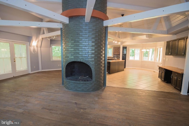 unfurnished living room with light wood-type flooring, vaulted ceiling with beams, french doors, plenty of natural light, and a fireplace