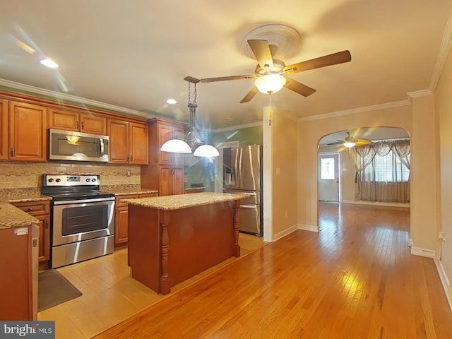 kitchen featuring light hardwood / wood-style flooring, stainless steel appliances, tasteful backsplash, a kitchen island, and decorative light fixtures