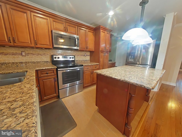 kitchen with light stone counters, backsplash, stainless steel appliances, and a center island