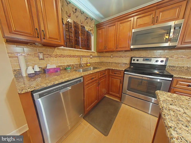 kitchen with light stone counters, sink, crown molding, and stainless steel appliances