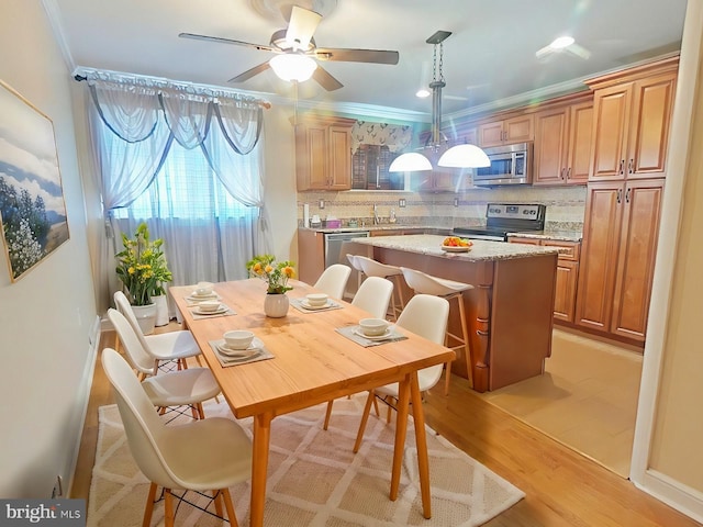 kitchen featuring crown molding, hanging light fixtures, a kitchen island, stainless steel appliances, and a kitchen bar