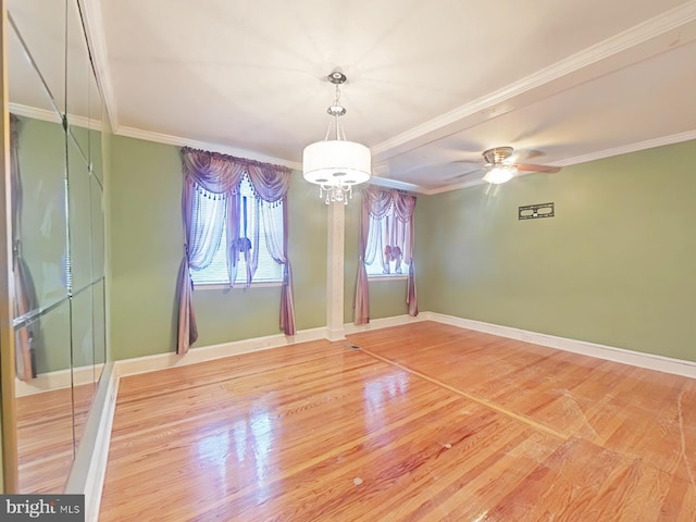 empty room featuring ornamental molding, wood-type flooring, and ceiling fan with notable chandelier