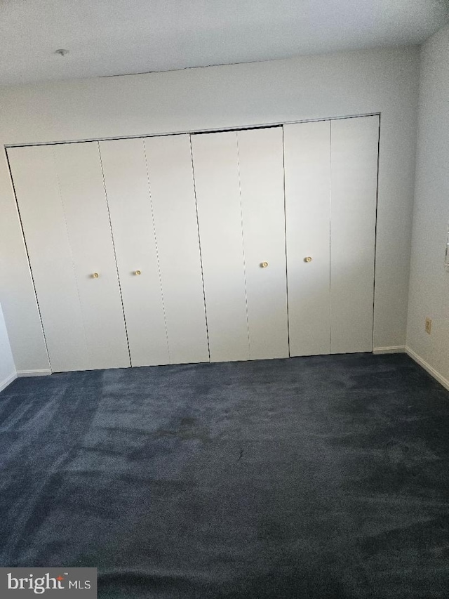 unfurnished bedroom with dark colored carpet