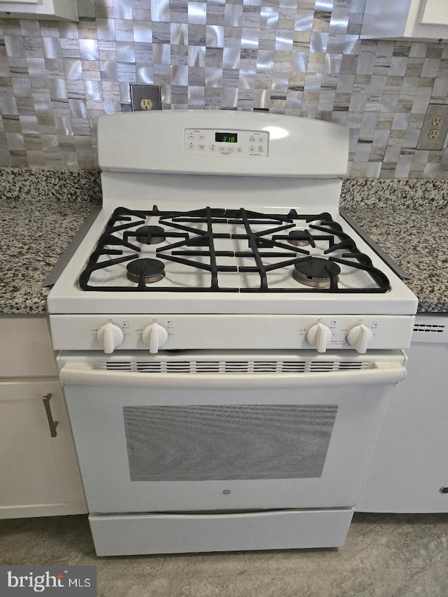 room details with light stone countertops, white cabinets, and white gas range oven