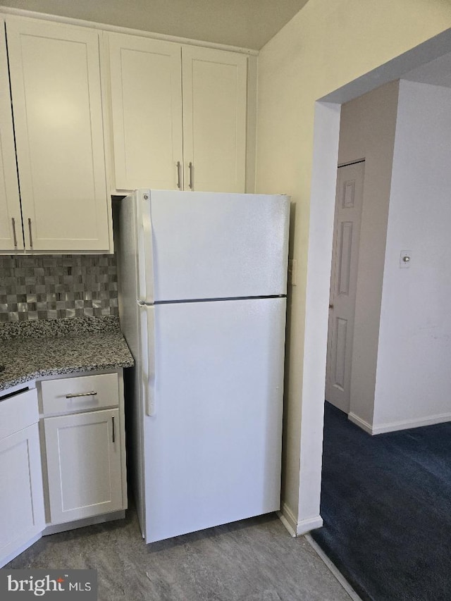 kitchen featuring decorative backsplash, light stone countertops, white cabinetry, and white fridge