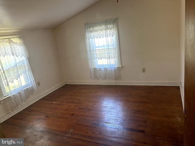 spare room with dark hardwood / wood-style flooring and vaulted ceiling