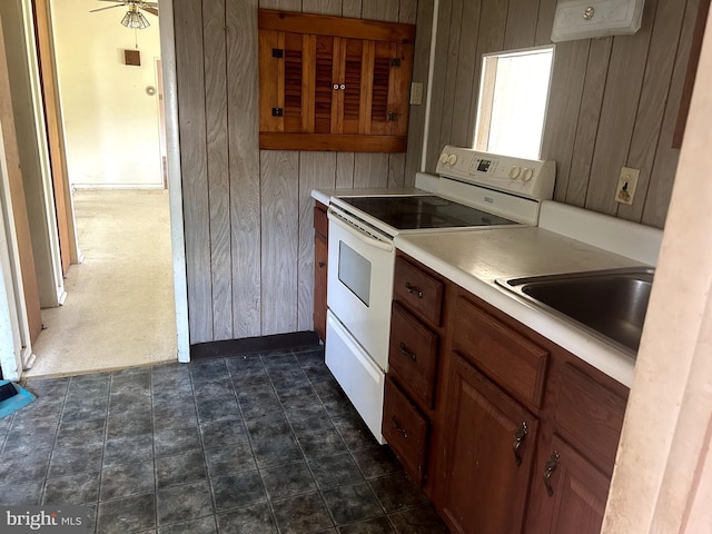 kitchen featuring ceiling fan, wood walls, white electric stove, and sink