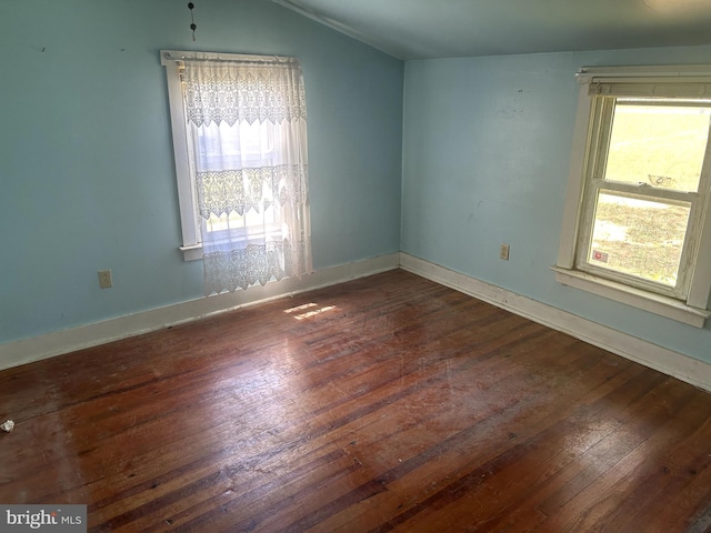 unfurnished room with vaulted ceiling, dark hardwood / wood-style floors, and plenty of natural light