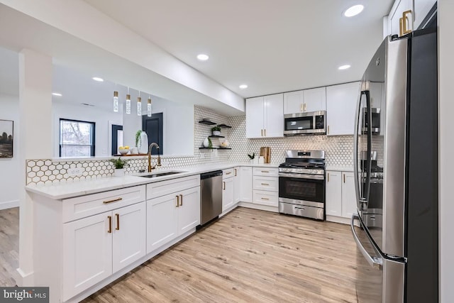 kitchen featuring decorative backsplash, sink, light wood-type flooring, stainless steel appliances, and white cabinets