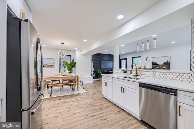 kitchen with appliances with stainless steel finishes, white cabinets, decorative light fixtures, and sink