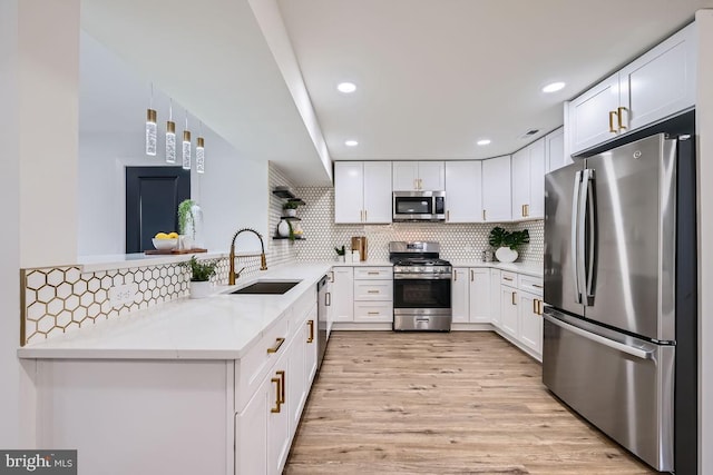 kitchen with light stone countertops, white cabinets, appliances with stainless steel finishes, sink, and kitchen peninsula