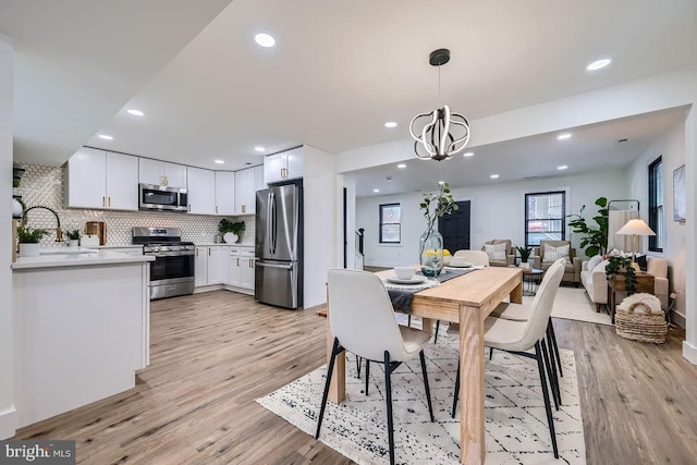 dining room with a notable chandelier, sink, and light hardwood / wood-style flooring