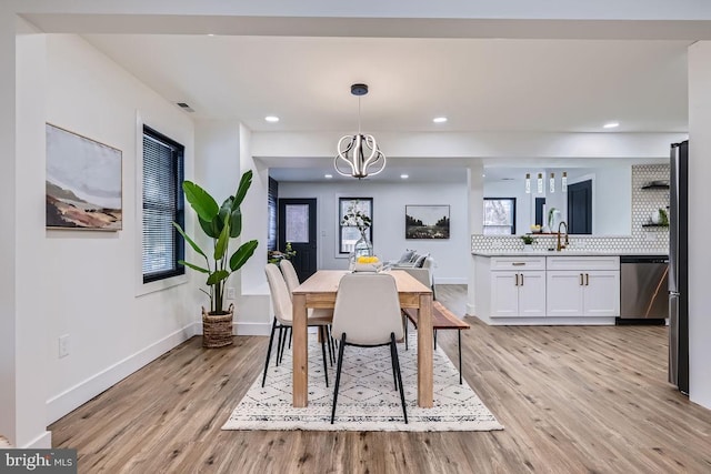 dining space featuring light wood-type flooring and an inviting chandelier