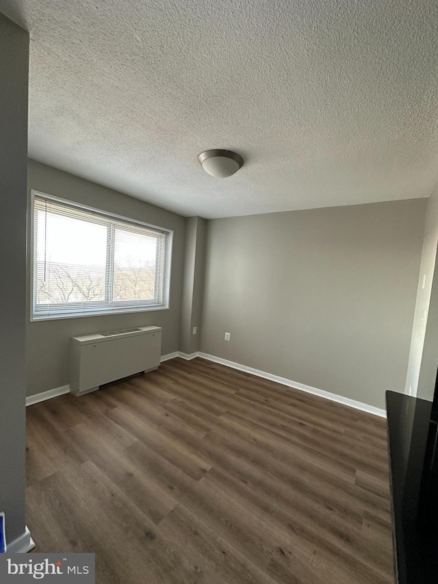 empty room featuring dark wood-type flooring and a textured ceiling