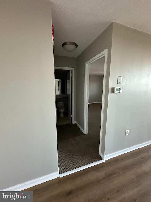 corridor with dark hardwood / wood-style floors and a textured ceiling