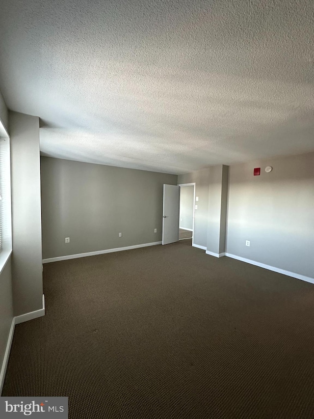 empty room with dark carpet and a textured ceiling