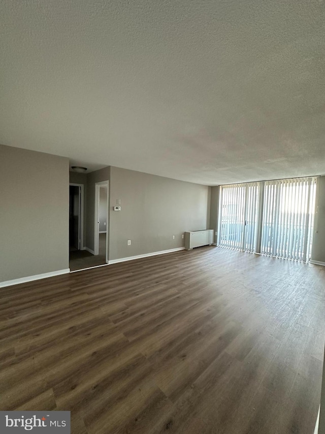 spare room with dark wood-type flooring, radiator, and a textured ceiling