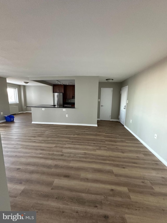 unfurnished living room with dark hardwood / wood-style flooring and a textured ceiling