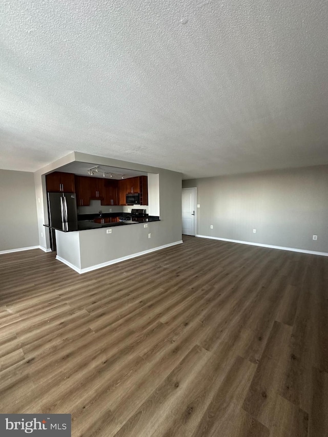 unfurnished living room with dark wood-type flooring and a textured ceiling