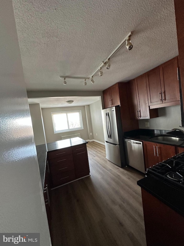 kitchen with hardwood / wood-style flooring, stainless steel appliances, sink, and a textured ceiling