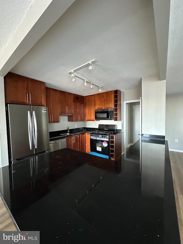 kitchen with stainless steel appliances, hardwood / wood-style flooring, sink, and a textured ceiling