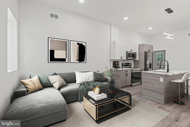 living room with light wood-type flooring, sink, and a high ceiling