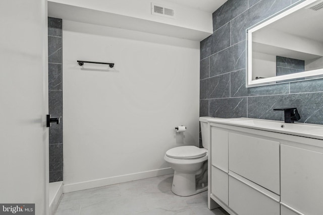 bathroom featuring toilet, vanity, tile walls, and walk in shower