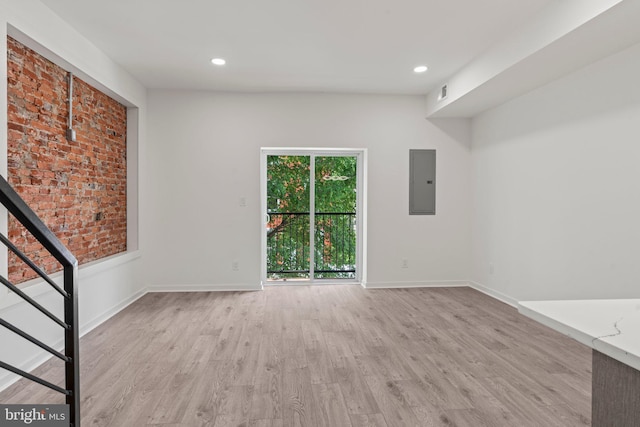 unfurnished living room with electric panel and light hardwood / wood-style floors