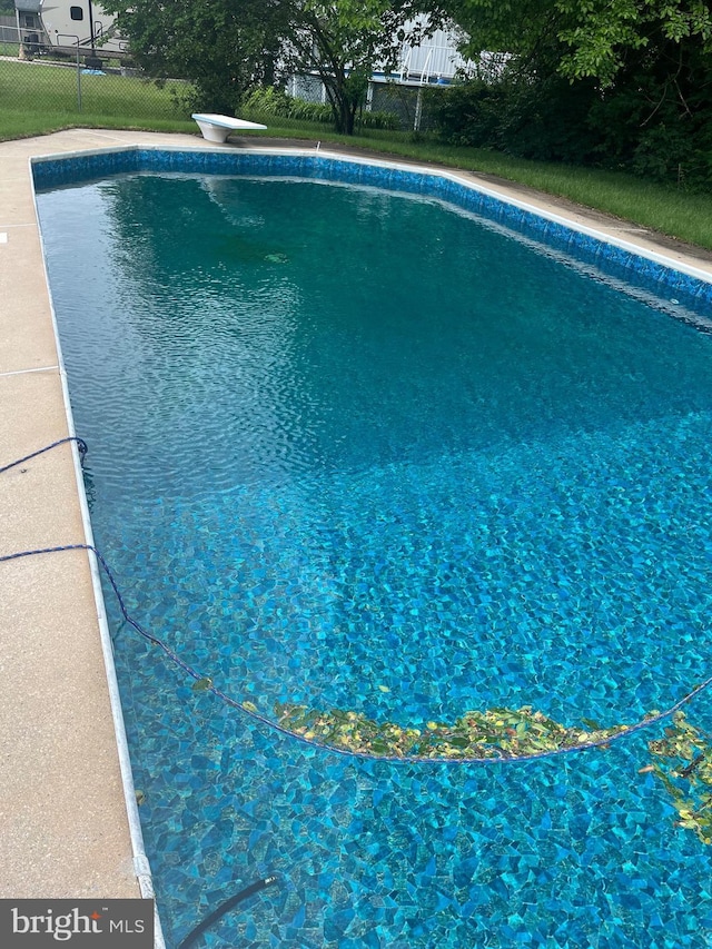 view of swimming pool featuring a diving board