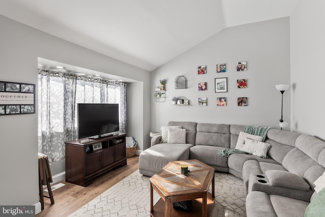 living room featuring lofted ceiling and light hardwood / wood-style flooring