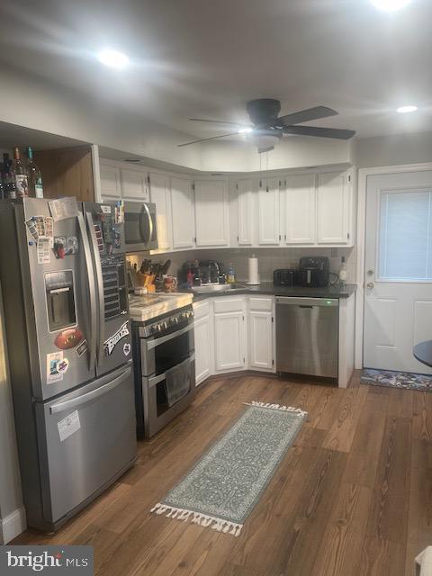 kitchen featuring sink, appliances with stainless steel finishes, white cabinetry, ceiling fan, and dark wood-type flooring