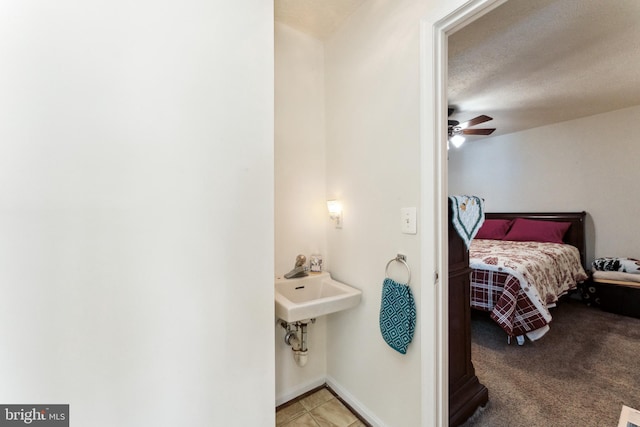 bedroom with light colored carpet, a textured ceiling, baseboards, and light tile patterned floors