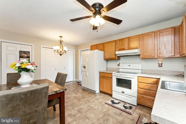 kitchen with decorative light fixtures, white appliances, light countertops, and under cabinet range hood