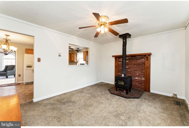 unfurnished living room with carpet, crown molding, visible vents, a ceiling fan, and a wood stove