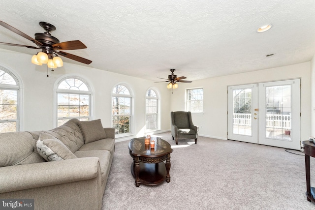 carpeted living area with a textured ceiling, ceiling fan, french doors, and baseboards