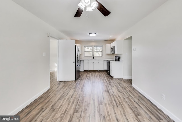 kitchen featuring ceiling fan, sink, white cabinetry, light hardwood / wood-style flooring, and stainless steel appliances