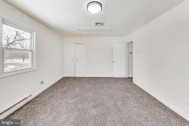 unfurnished bedroom with baseboard heating, carpet, and a closet