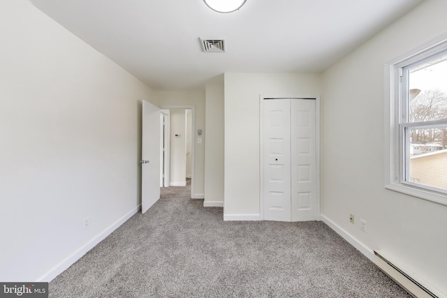 unfurnished bedroom with light carpet, a baseboard heating unit, a closet, and multiple windows