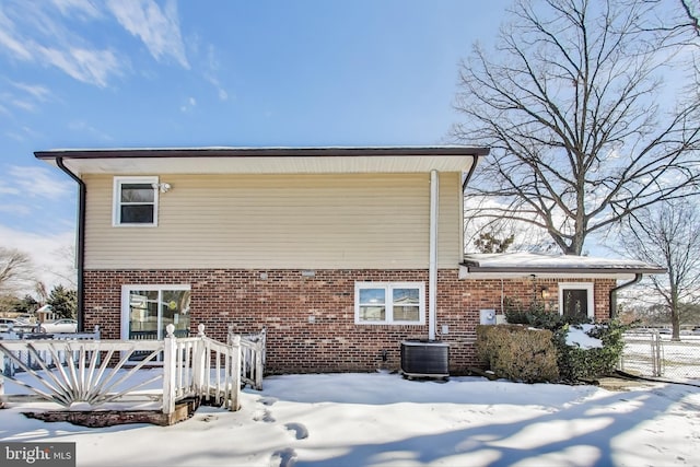 snow covered house featuring a wooden deck and cooling unit