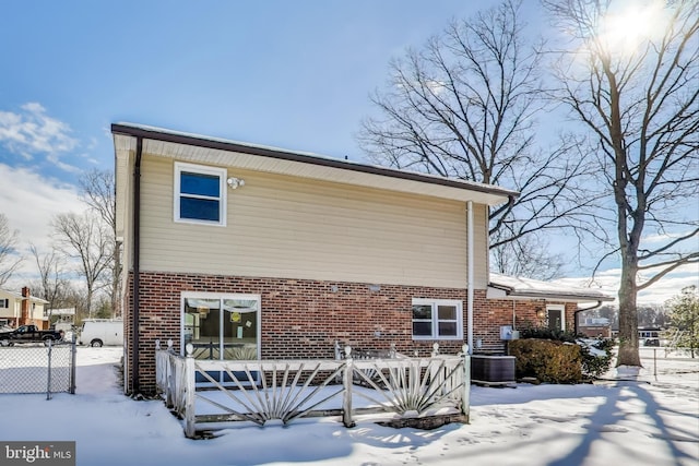 snow covered house featuring cooling unit