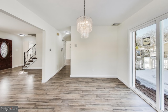 unfurnished dining area featuring light wood-type flooring and a notable chandelier