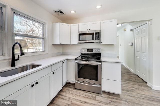 kitchen featuring sink, white cabinetry, stainless steel appliances, and light wood-type flooring