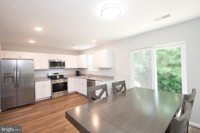 kitchen featuring stainless steel appliances, hardwood / wood-style floors, white cabinetry, and sink