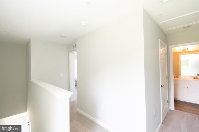 hallway with light carpet and sink