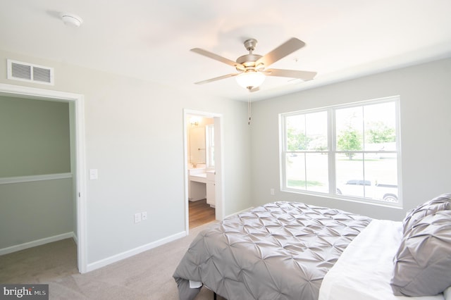 bedroom with ensuite bathroom, ceiling fan, and light carpet