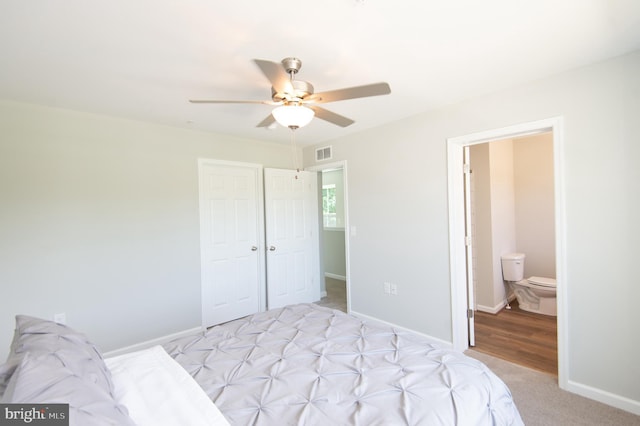 bedroom with ceiling fan, light carpet, and ensuite bath